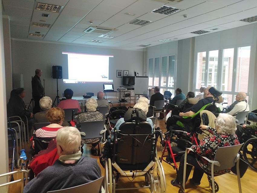 Un representante del Banco de Alimentos de Bizkaia habla ante un grupo de personas mayores en una sala